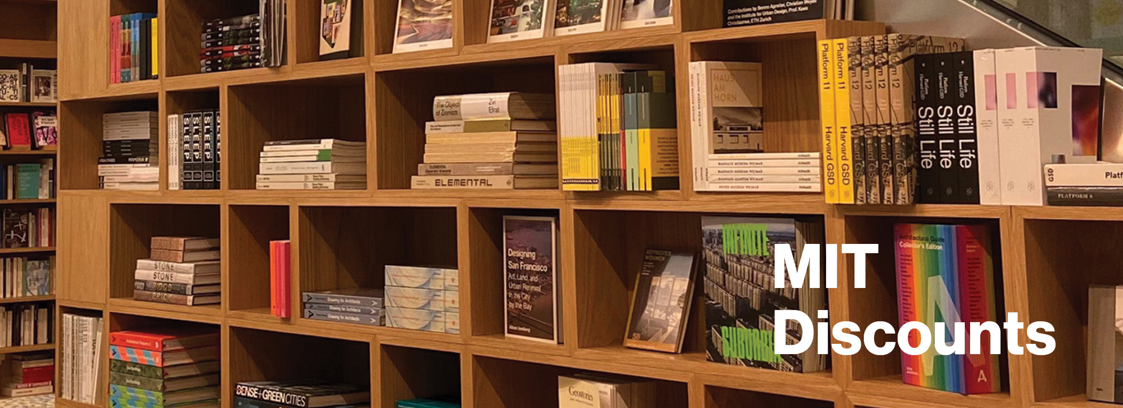 The words MIT Discounts is overlaid a photo of a blonde wood bookcase is packed with colorful books.
